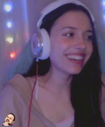 a woman wearing headphones and a hat is smiling while looking at the camera .