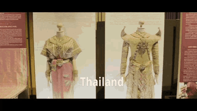 two mannequins are displayed in front of a sign that says thailand on it