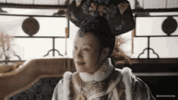 a woman in a traditional costume with a crown on her head is sitting on a couch .