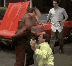 two men are fighting in front of a corvette