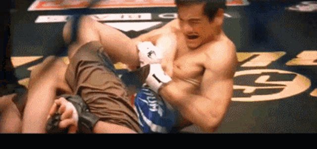 two men are wrestling in a ring with the letter g on the ground
