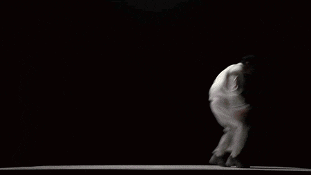 a man in white pants and a white shirt is dancing in the dark