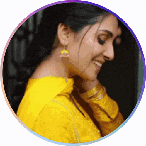 a woman wearing a yellow shirt and earrings is smiling