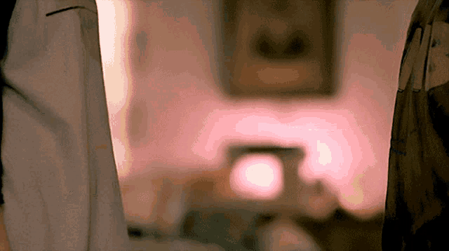 a blurred image of a room with a pink light and a picture on the wall
