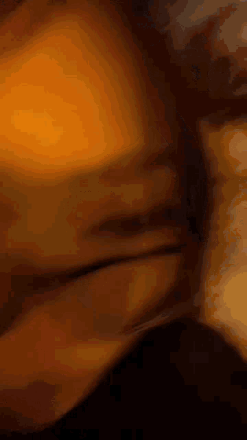 a blurry picture of a person 's face in a dark room with a yellow background .
