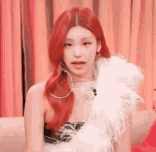 a close up of a woman with red hair wearing a white feather boa .