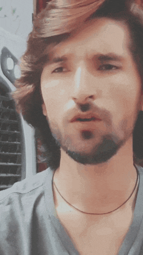 a man with long hair and a beard is wearing a gray shirt