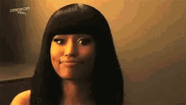 a woman with long black hair and bangs is smiling and looking at the camera .