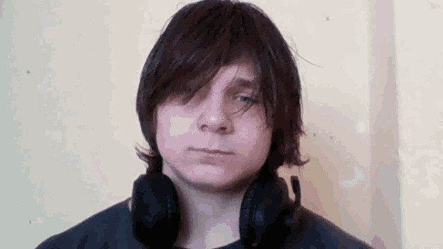 a young man is wearing headphones around his neck and looking at the camera .