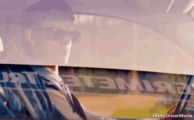 a man wearing sunglasses is driving a car with the words baby driver movie written on the windshield