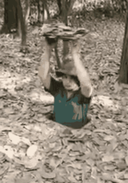 a man is crawling through a hole in the ground while holding a large rock over his head .