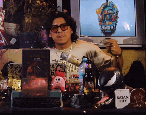 a man sitting in front of a tv with a sign that says satan city on it