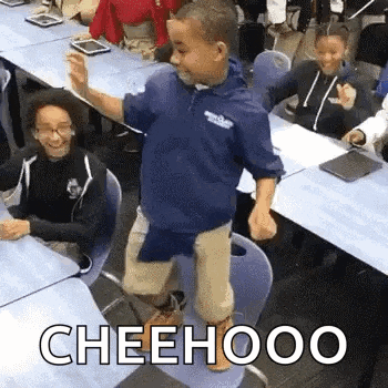 a young boy is dancing in a classroom while sitting at a desk .