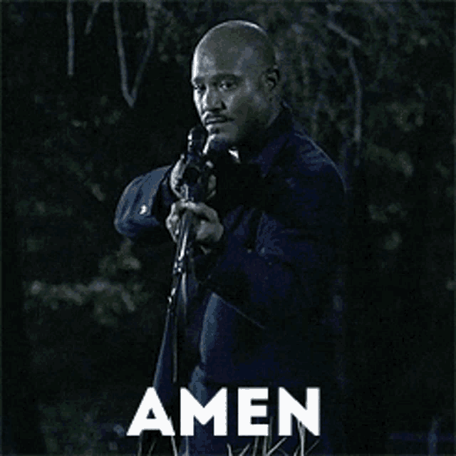 a man holding a gun in front of a sign that reads amen