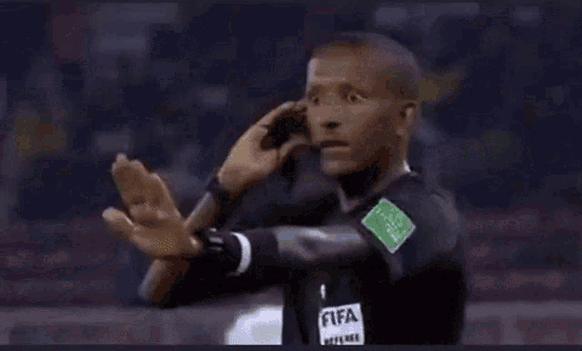 a referee wearing a black shirt that says fifa on the sleeve