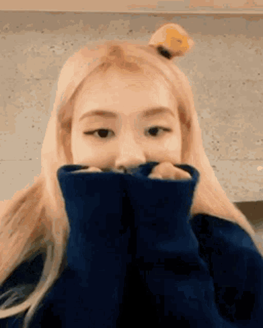 a close up of a person wearing a blue sweater covering their face .