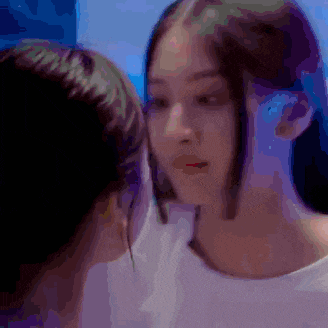 two women are looking at each other in a dark room .