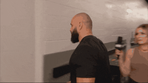 a man with a beard stands next to a woman holding a cup