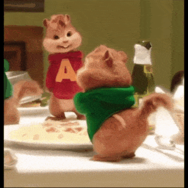 two alvin and chipmunks are standing next to each other on a table
