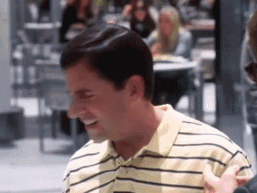 a man wearing a yellow and black striped shirt is smiling and talking to someone