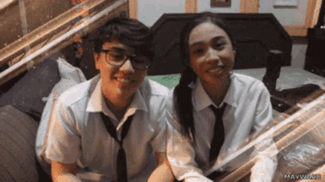 a boy and a girl are sitting next to each other and smiling for the camera