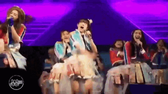 a group of girls are singing into microphones on stage