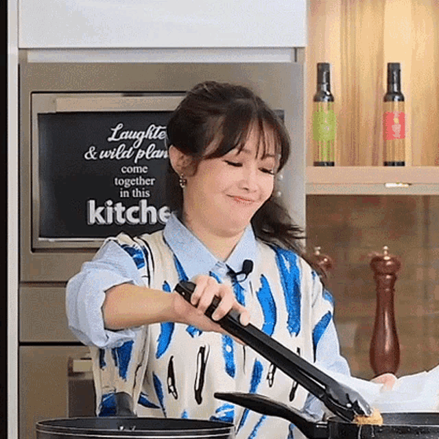 a woman is cooking in front of a sign that says " laughs & wild plans come together in this kitchen "
