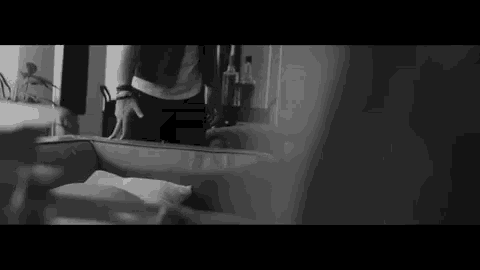 a black and white photo of a person standing next to a couch