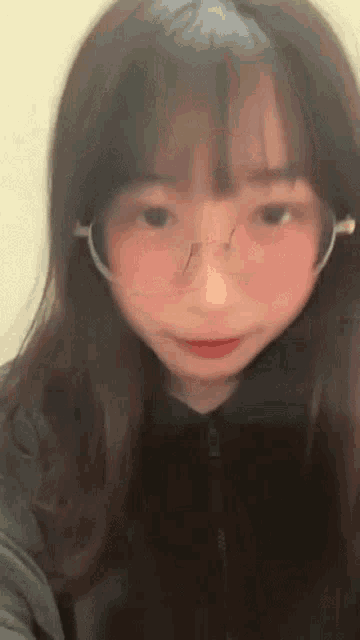 a girl wearing glasses and a mask is looking at the camera .