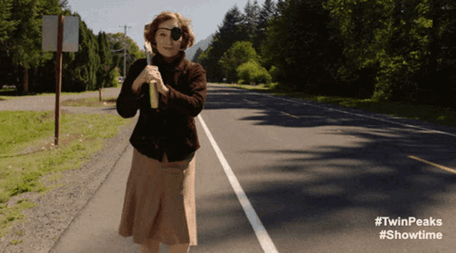 a woman with an eye patch is walking down a road with #twinpeaks #showtime written on the bottom