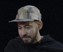 a man with a beard is wearing a hat and a hoodie and laughing .
