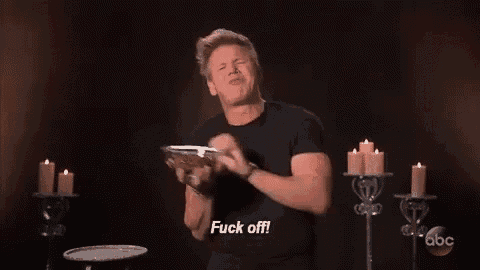 a man in a black shirt is standing in front of candles and holding a glass .