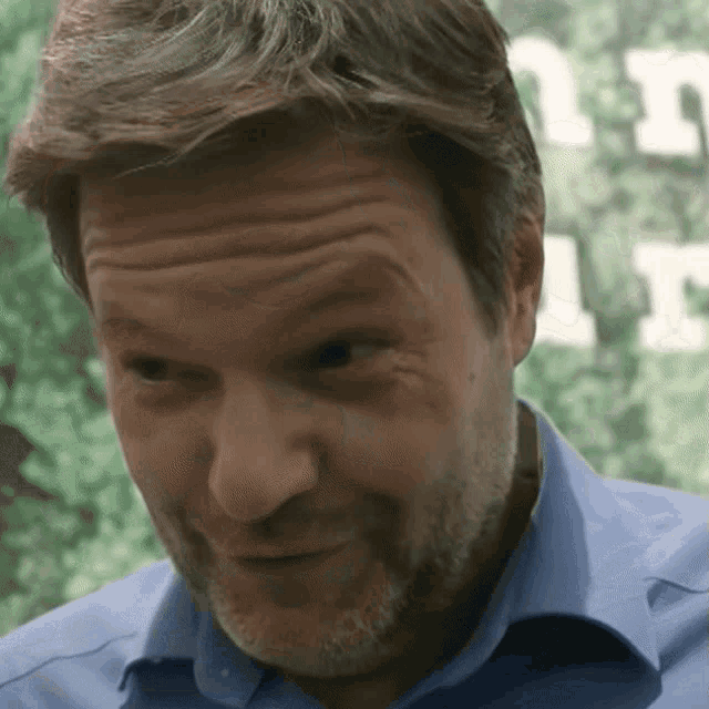 a man with a beard wearing a blue shirt is making a funny face