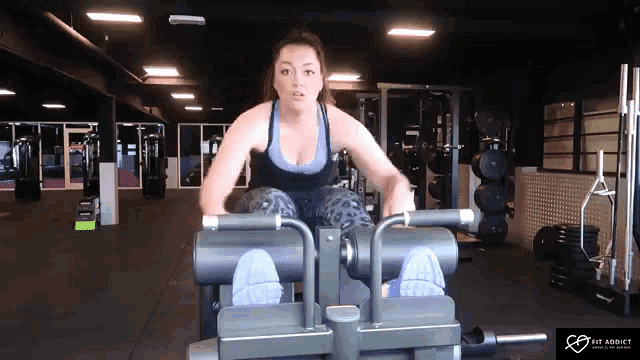 a woman is using a machine in a gym that says fit addict on it