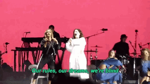 a group of women singing on a stage with the words our rules our dreams we 're blind