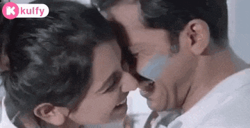 a man and a woman are kissing each other in a room .