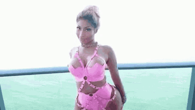 a woman is standing on a balcony wearing a pink swimsuit .