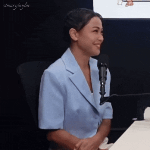 a woman in a blue jacket is sitting in front of a microphone ..