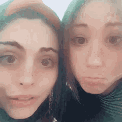 two women are posing for a picture and making funny faces with their mouths open .