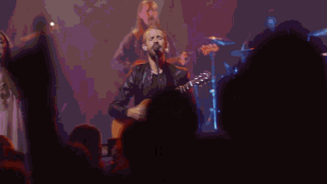 a man with long hair is playing drums in a band