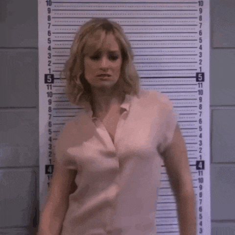 a woman in a pink shirt stands in front of a ruler that goes up to 12