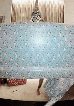 a christmas tree is behind a large sheet of wrapping paper