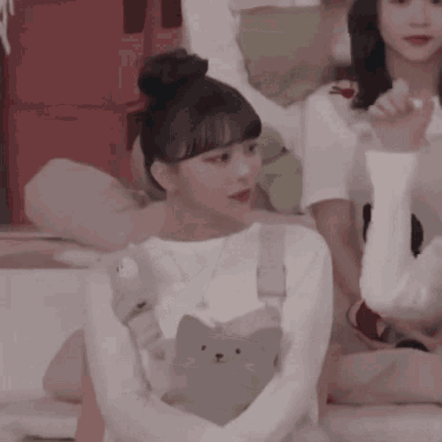 a woman in a white shirt with a cat on the chest is sitting on a couch .