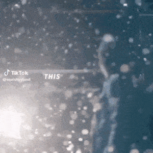 a person is standing in a dark room with snow falling .