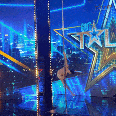 a pole dancer performs on a stage in front of a got talent logo