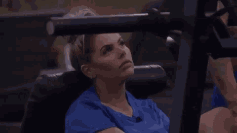 a woman in a blue shirt is sitting on a machine in a gym .