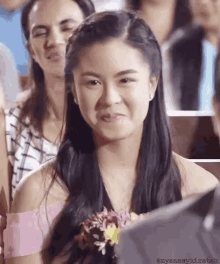 a woman is making a funny face while sitting in a crowd .