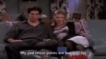 a man and a woman are sitting on a couch and the man is giving the peace sign .