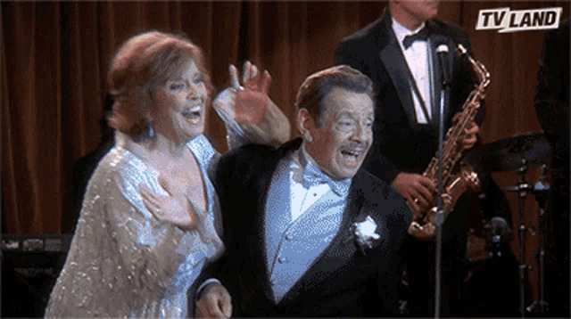a man in a tuxedo and a woman in a dress are on a stage with a tv land logo