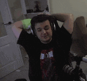 a man wearing headphones is sitting in a chair with his fist in the air while holding a stuffed animal .